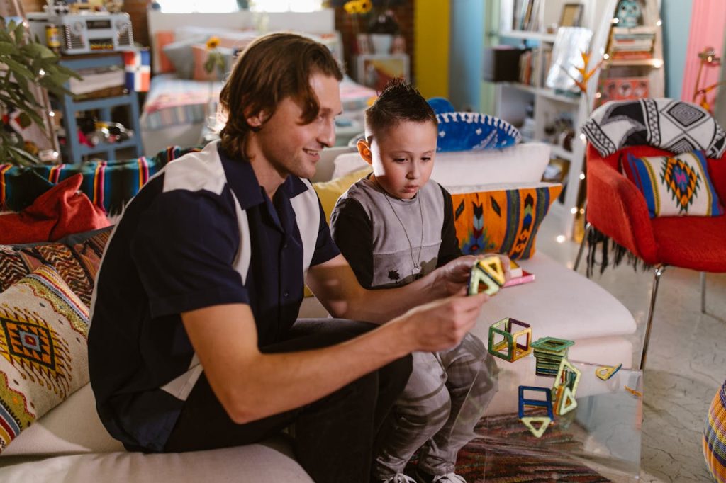 A father and son enjoy quality time playing with colorful magnetic blocks indoors.
