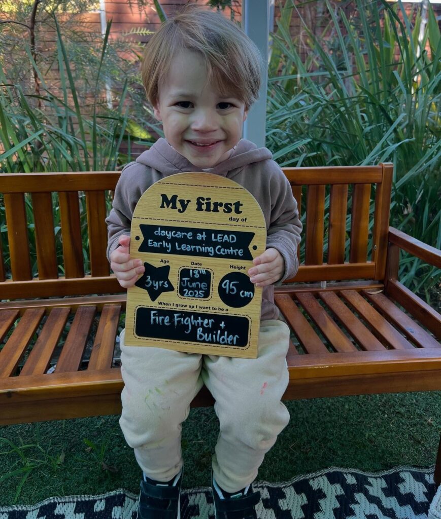 509288913_17858898468439206_2277753938097887553_n Smiling child holding milestone board on their first day at St Ives day care